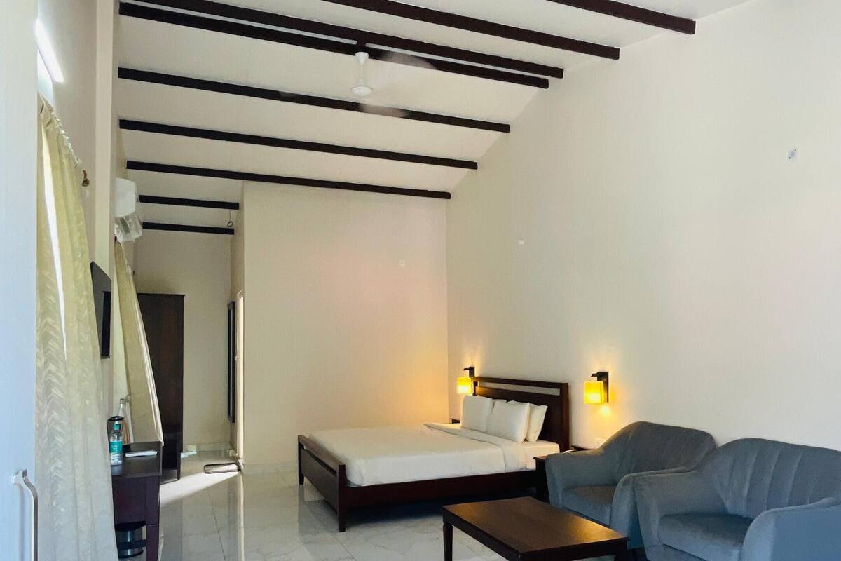 Een moderne hotelkamer met een bed, een bank, een bijzettafeltje en een televisie.