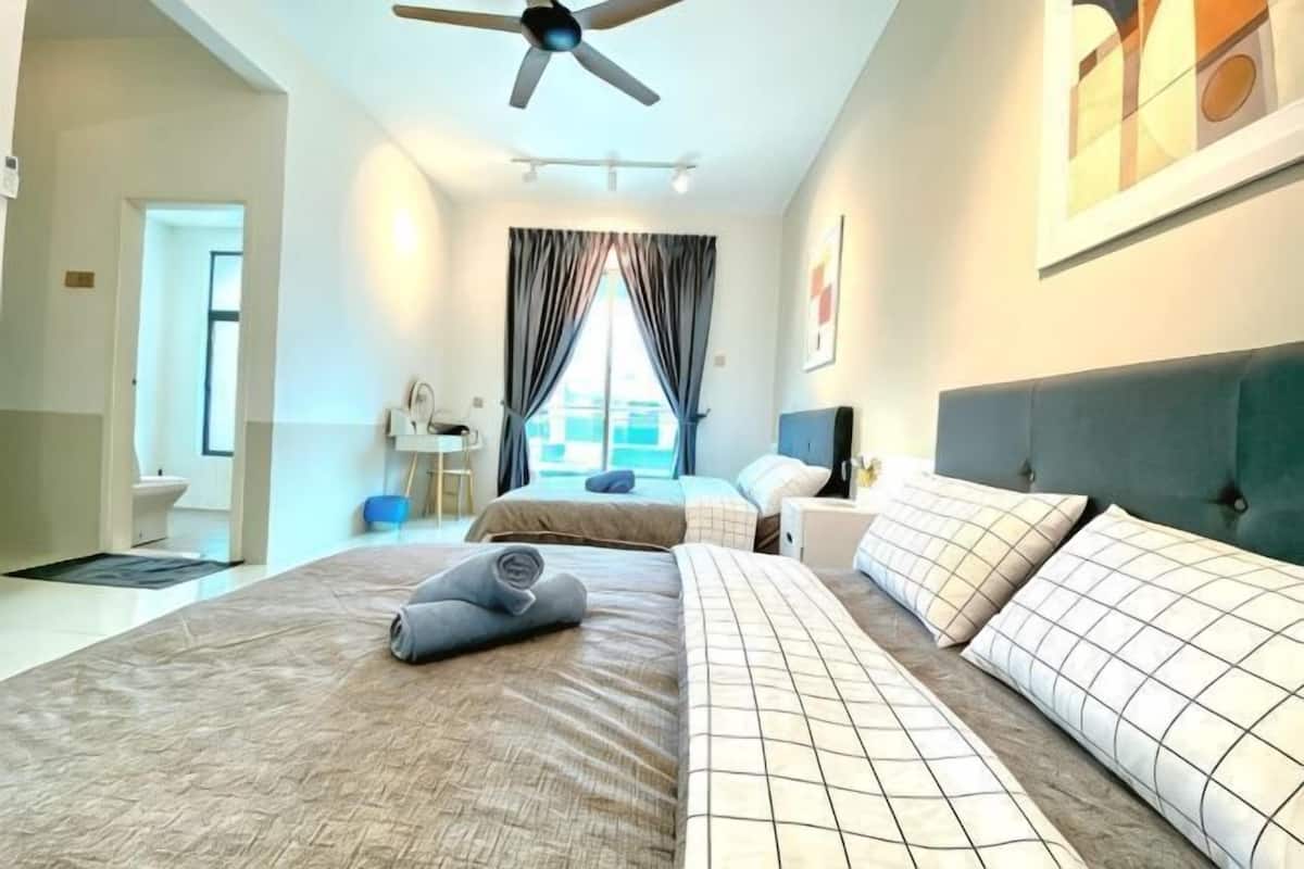 A hotel room with a bed, a desk, a chair, a ceiling fan, and a window with curtains.