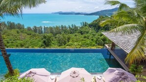 A pool with clear blue water, surrounded by lush greenery and a view of the ocean. - The Sawan (Phuket)