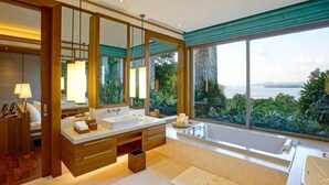 A modern bathroom with dual sinks, a large mirror, and a view of the sea. - The Sawan (Phuket)