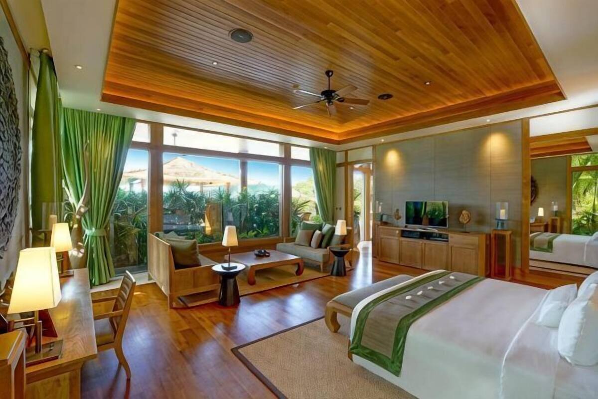 A spacious bedroom with a large bed, a sitting area, and a TV.