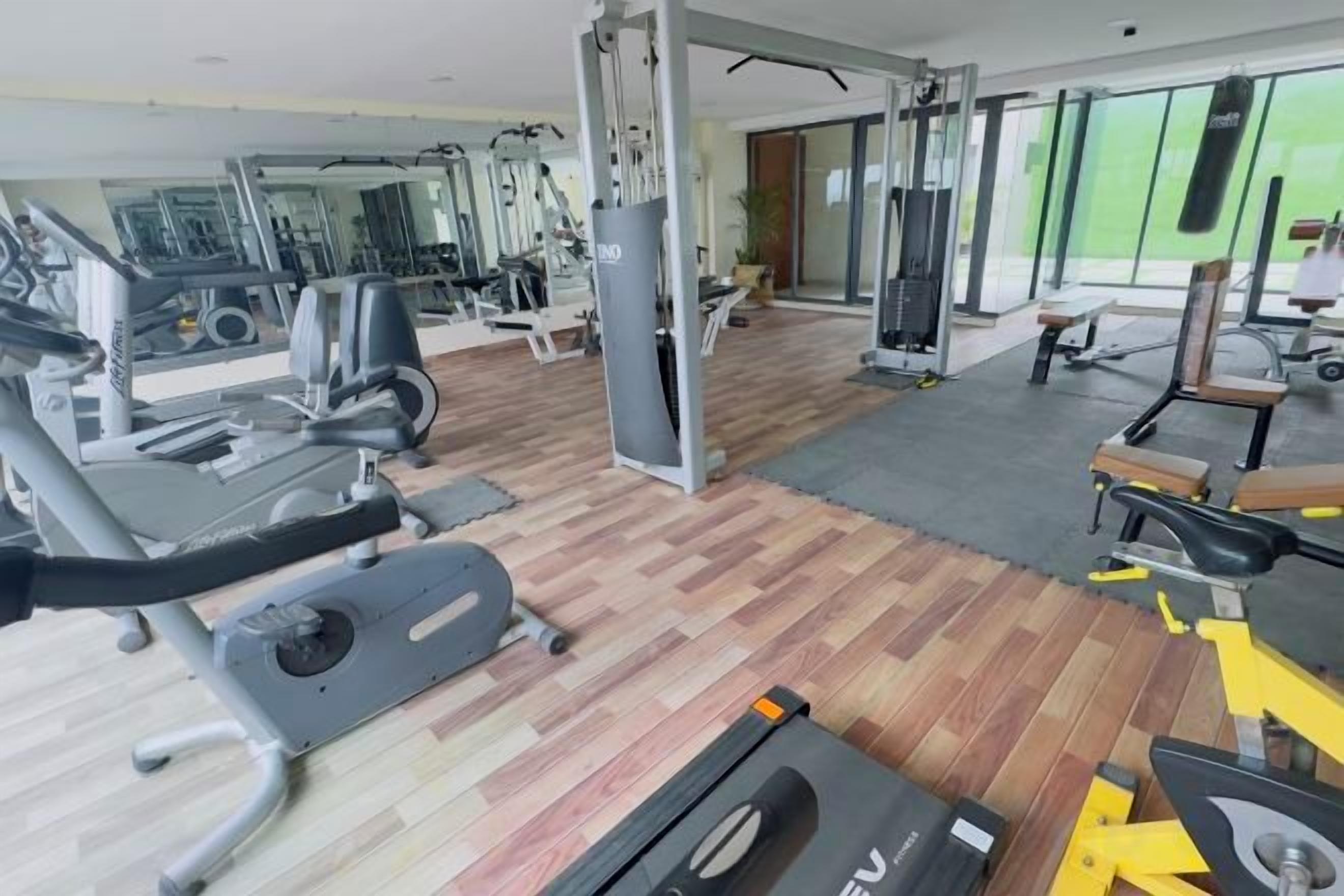 A gym with exercise equipment, a wooden floor, and a green wall.