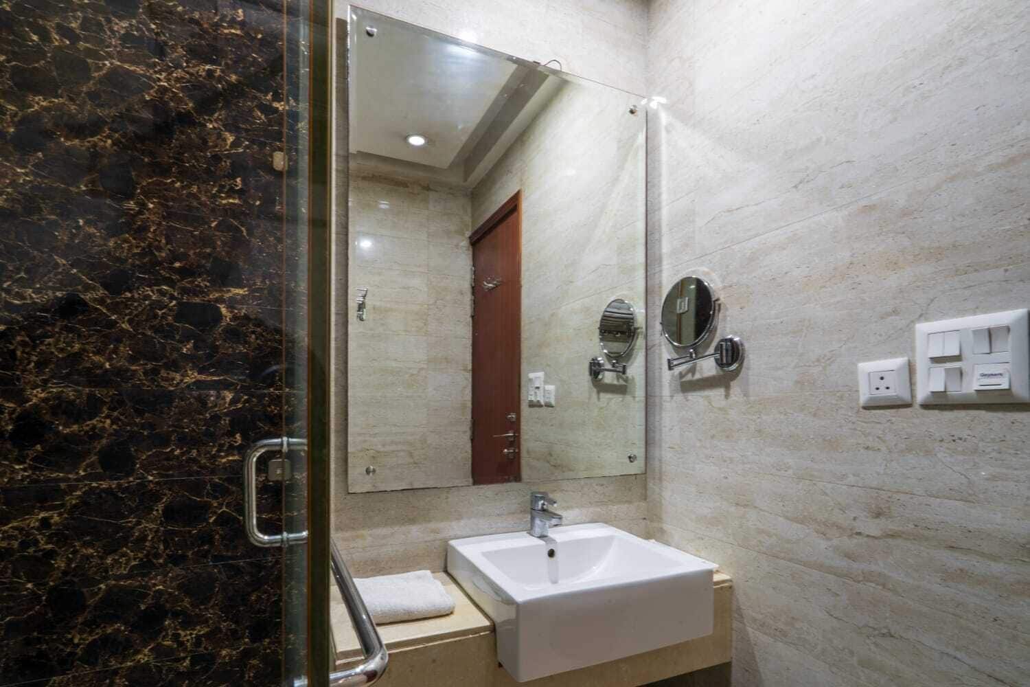 A bathroom with a marble wall, a white sink, a mirror, and a door.