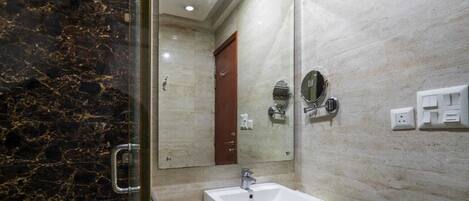 A bathroom with a marble wall, a white sink, a mirror, and a door.
