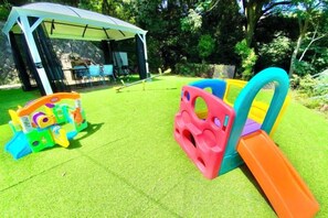 A children's play area with a slide and climbing structure, a covered seating area, and a grassy lawn. - Blue Ocean Izu (Atami)