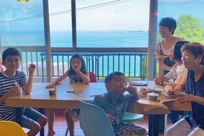 Un groupe de personnes est assis autour d’une table, avec vue sur la mer.