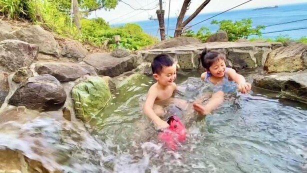 Two children playing in a natural water feature surrounded by rocks and greenery. - Blue Ocean Izu (Atami)