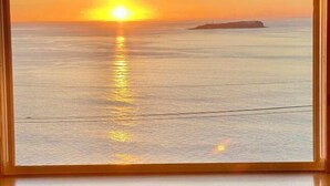 Una vista incorniciata di un tramonto sull'oceano con una piccola isola all'orizzonte.