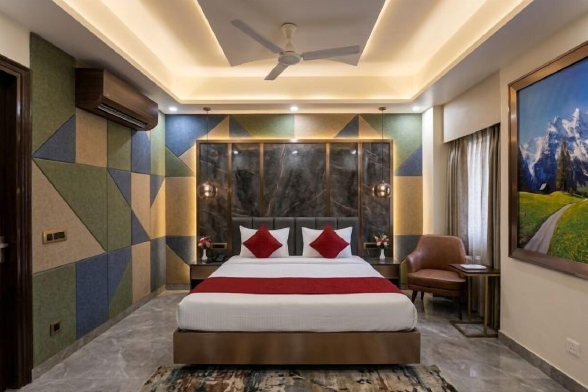 Une chambre à coucher avec un grand lit, un ventilateur de plafond, une table de chevet et un tableau au mur.