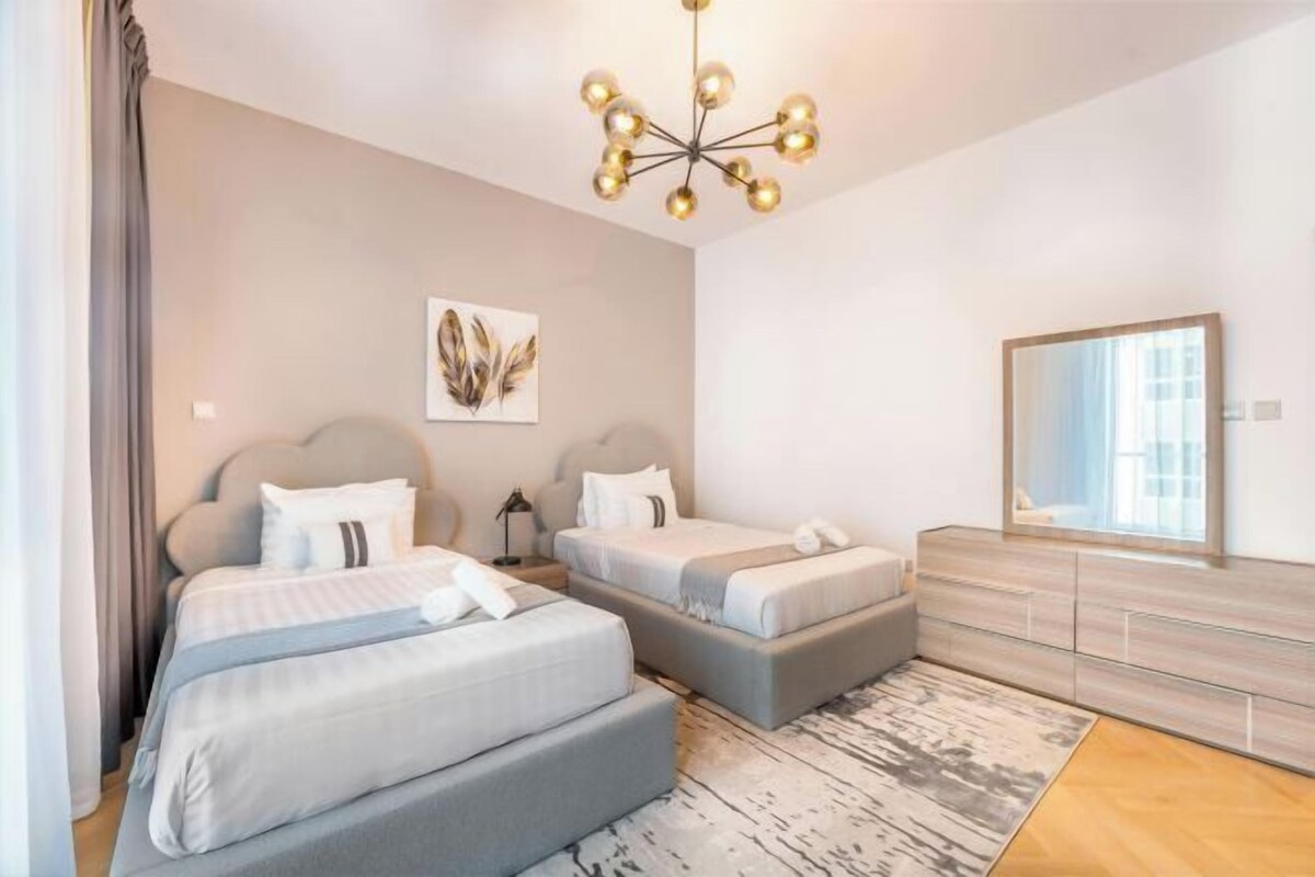 Ein modernes Hotelzimmer mit zwei Betten, einem großen Spiegel und einer Chandelüster.