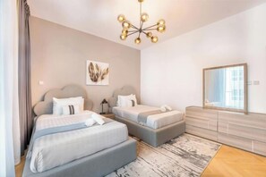 Ein modernes Hotelzimmer mit zwei Betten, einem großen Spiegel und einer Chandelüster.