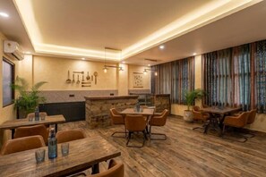 Een restaurant met houten vloeren, tafels, stoelen, een bar en decoratieve muurkunst.