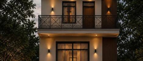 A multi-story building with balconies, large windows, and exterior lighting.