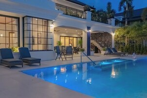 Un área de piscina moderna con sillones reclinables y una escalera que conduce a un nivel superior.