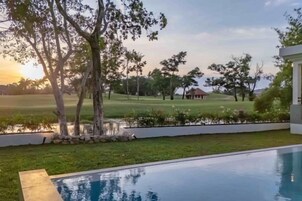 Una piscina con vista a un campo de golf y árboles.