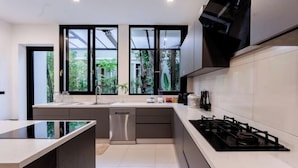Cocina moderna con una isla central, electrodomésticos de acero inoxidable y ventanas amplias con vistas a zonas verdes.