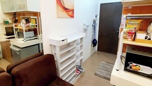 A compact living space with a kitchenette, a dining area, and a TV. - Contemporary Maison Studio Unit at Ortigas Center Pasig (Pasig)