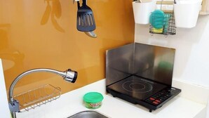 A kitchen with a stainless steel sink, a built-in stovetop, and a dish rack. - Contemporary Maison Studio Unit at Ortigas Center Pasig (Pasig)