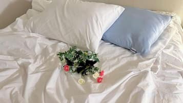 A bed with white and blue pillows and a bouquet of flowers on the bed.