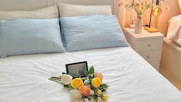 A neatly made bed with a bouquet of flowers and a framed photo on the bed.