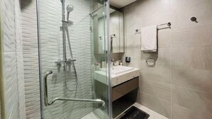 Een moderne badkamer met een douche met glazen wand, een wastafel met spiegel en een handdoekrek.