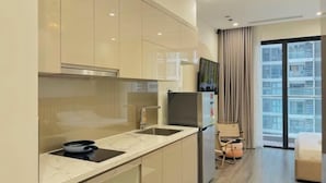 Een moderne keuken met een marmeren aanrechtblad, roestvrijstalen apparatuur en een schuifdeur naar een balkon met uitzicht op de stad.
