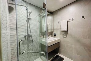 Une salle de bain moderne avec une douche à parois de verre, un lavabo et un miroir.