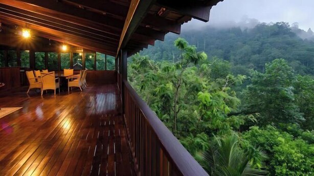 A wooden deck with a table and chairs, overlooking a lush forest. - Deserenity Exclusive Jungle Resort Seremban (Seremban)