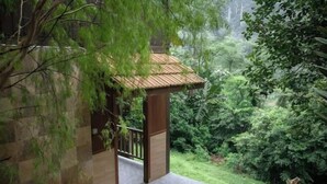 A covered outdoor area with a wooden structure, a stone wall, and lush greenery. - Deserenity Exclusive Jungle Resort Seremban (Seremban)