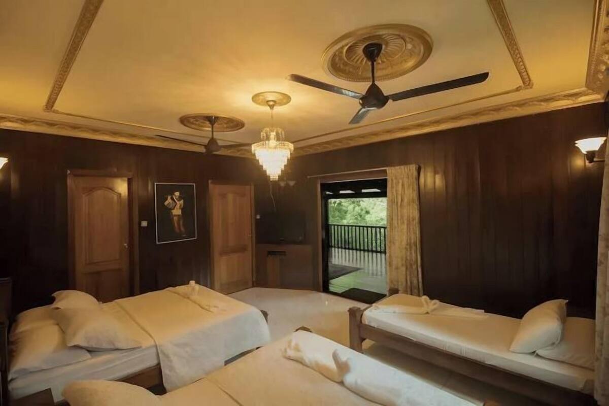 Una habitación con dos camas, ventilador de techo, candelabro y puerta que da a un espacio al aire libre.