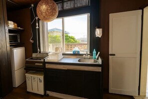 A compact kitchen with a window, a microwave, a sink, and a refrigerator. - Nukanuka ぬかぬか (Miyakojima)