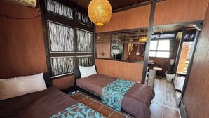 Une chambre d’hôtel avec deux lits, une tête de lit en bois, un luminaire suspendu et une vue sur la salle à manger.