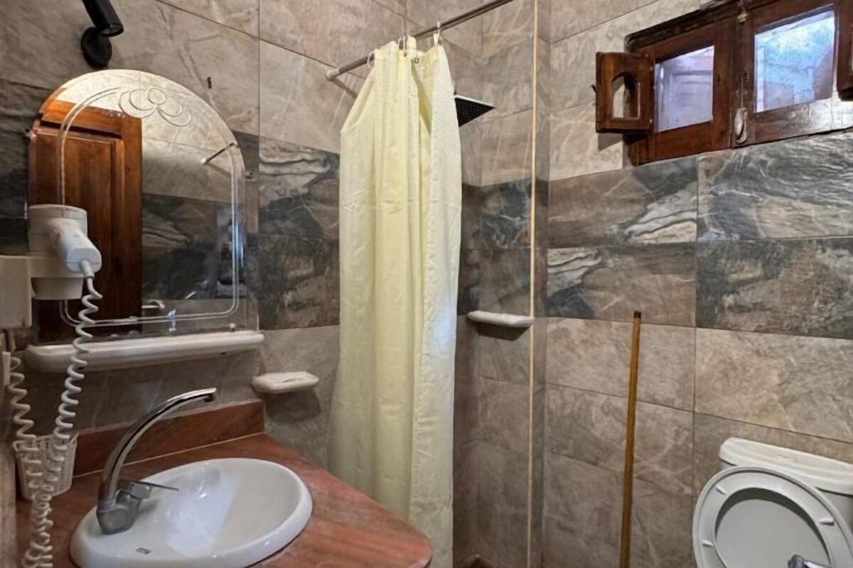 A bathroom with a sink, mirror, shower curtain, and a wooden cabinet.