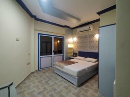 A bedroom with a bed, a wardrobe, a nightstand, and an air conditioning unit.