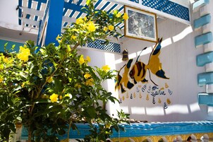 A building facade with a decorative mural, a blue and white color scheme, and a balcony with blue railings.