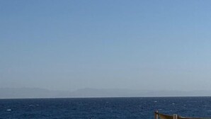 Una vista limpida sull'oceano, con terraferma in lontananza e una barca in primo piano.