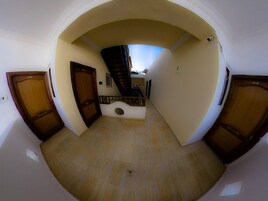 A hallway with a wooden staircase leading to an upper level, a door on the left, and a door on the right.