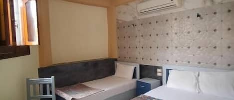 A bedroom with two beds, a small table, and a chair.
