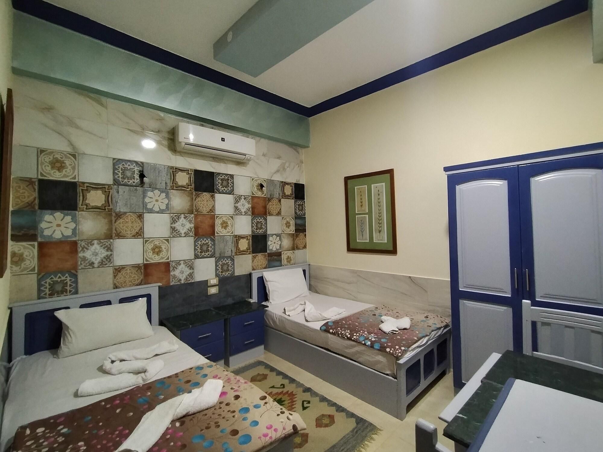 A bedroom with two beds, a wardrobe, a tiled wall, and an air conditioning unit.