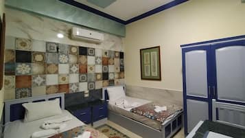 A bedroom with two beds, a wardrobe, a tiled wall, and an air conditioning unit.