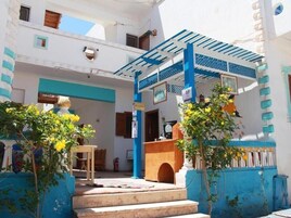 Un patio con una escalera que lleva a un área cubierta, un banco de madera y una pequeña mesa.