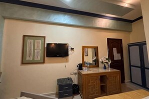 Ένα υπνοδωμάτιο με ένα κρεβάτι, μια συρταριέρα, μια τηλεόραση τοποθετημένη στον τοίχο και έναν καθρέφτη.