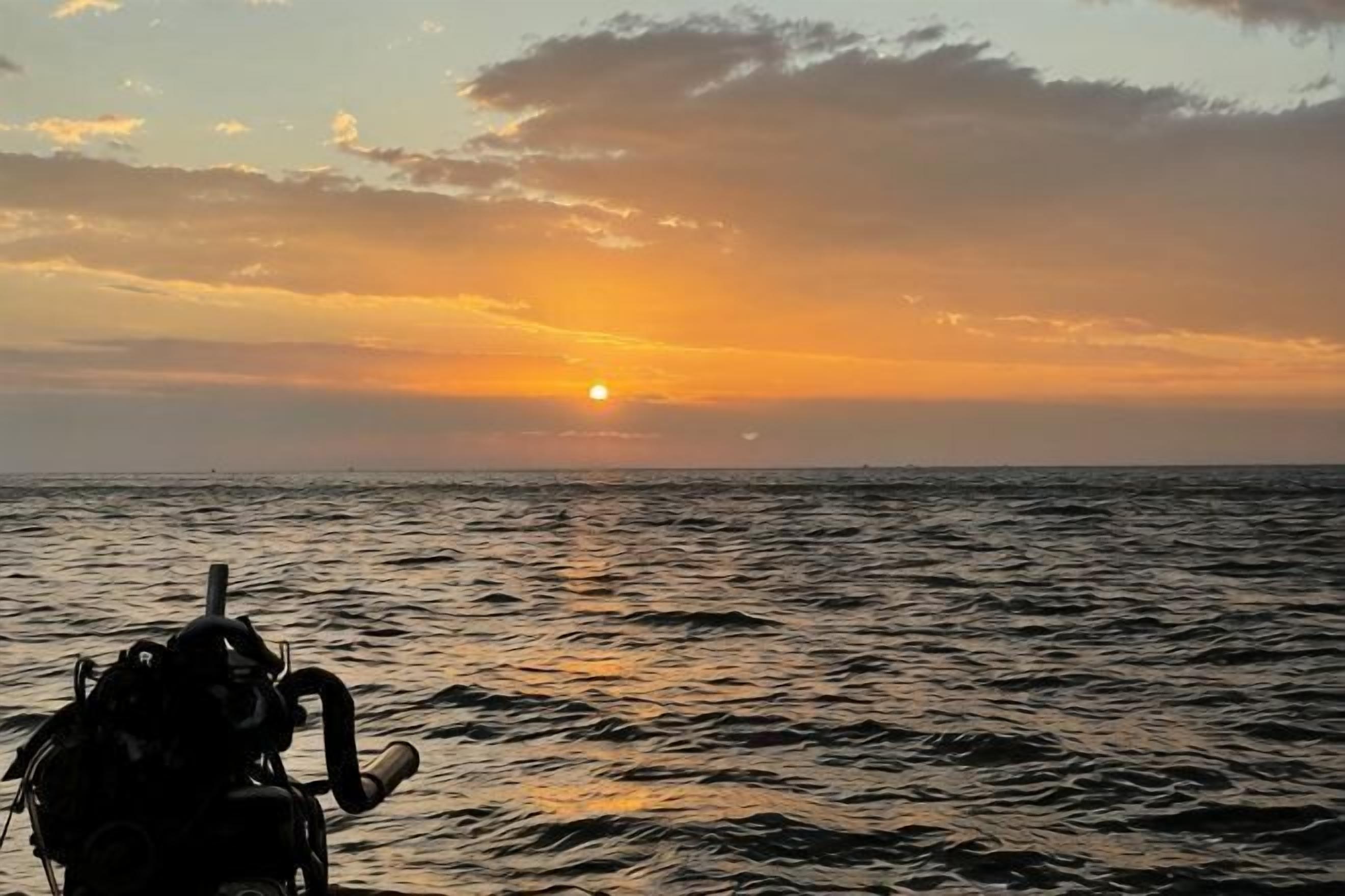 Un coucher de soleil sur l’océan, avec une moto au premier plan.