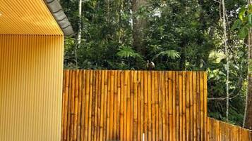 A room with a bamboo wall, a white bathtub, and a yellow exterior wall.