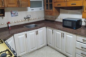 Una cocina con armarios blancos, encimera de granito, microondas y fregadero.