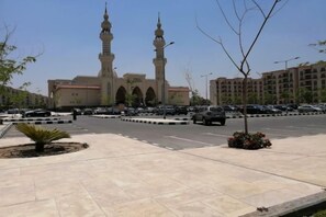 Une mosquée dotée de deux minarets, d’un parking et d’un ciel dégagé.