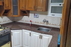 Una cocina con armarios de madera, estufa a gas, pileta y una ventana sobre la encimera.