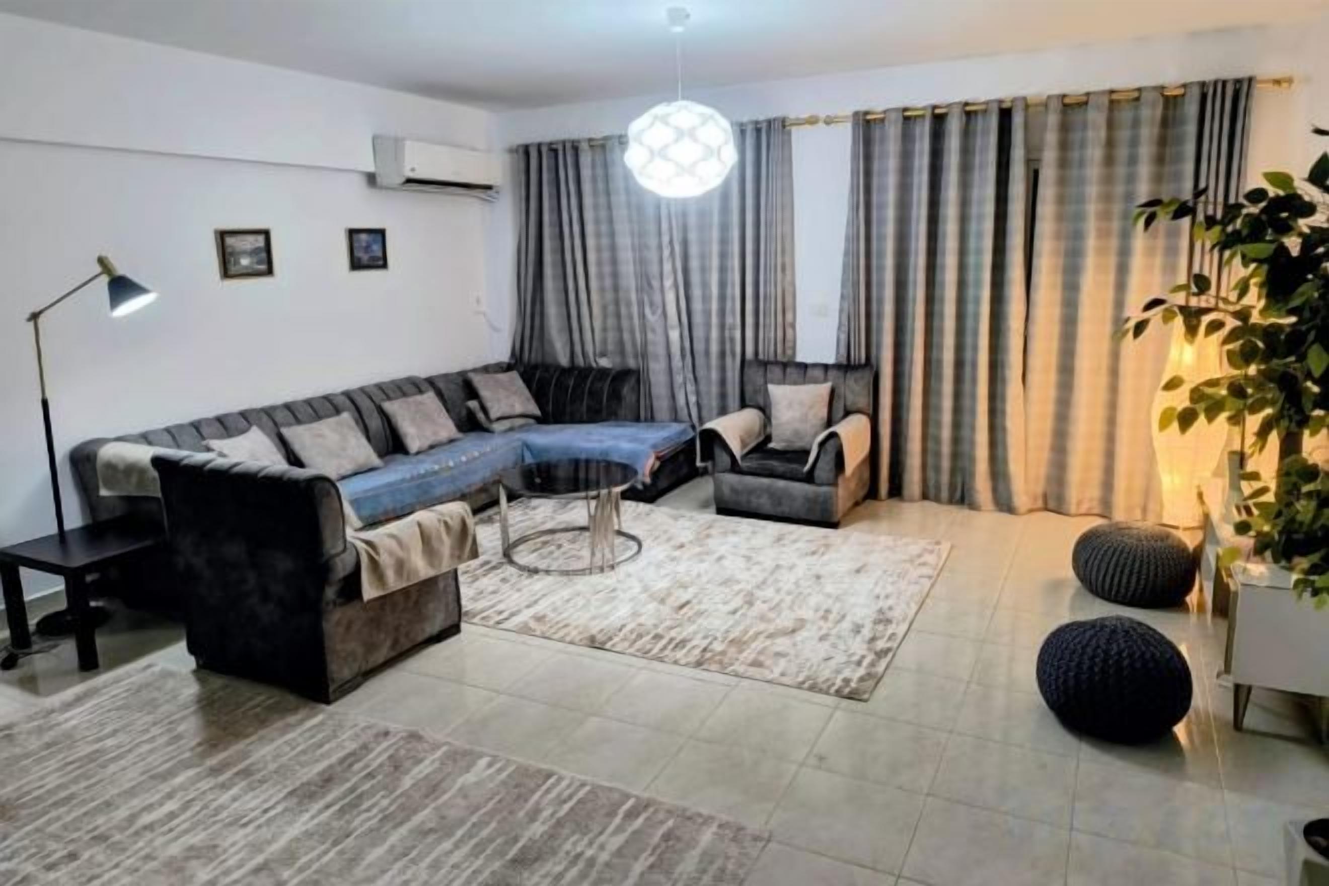 Un salon moderne avec un canapé d’angle, une table basse et un lampadaire.