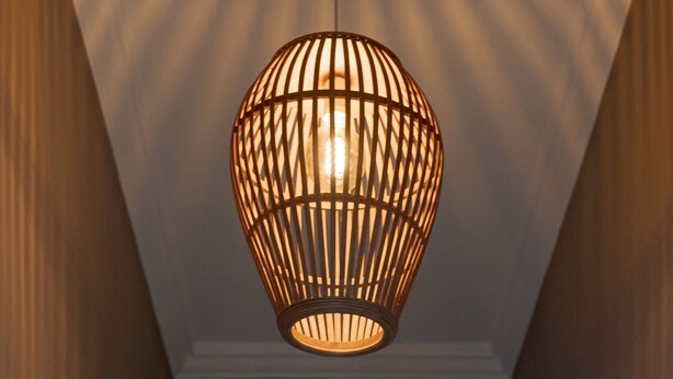 A spherical pendant light fixture with a grid pattern, hanging from a ceiling with a visible electrical outlet. - Elaia House Glyfada (Glyfada)