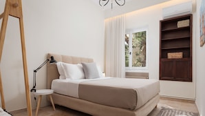 A bedroom with a bed, bedside lamp, and a window with curtains. - Elaia House Glyfada (Glyfada)